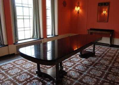 Polished wooden table in a room with a patterned carpet.