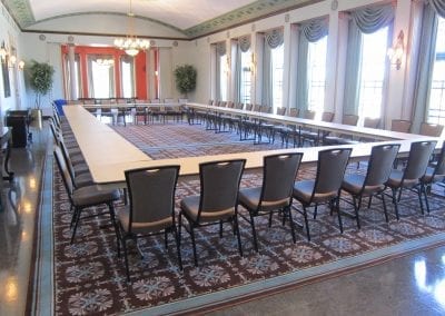 A spacious conference room with a large table arrangement and elegantly patterned carpet.