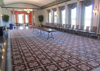 Elegant meeting room with a long table, patterned carpet, and several chairs against the wall.