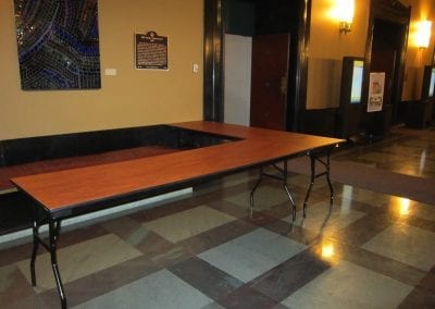 A long table in the Rackham Building hallway with checkered flooring and doors on the side.