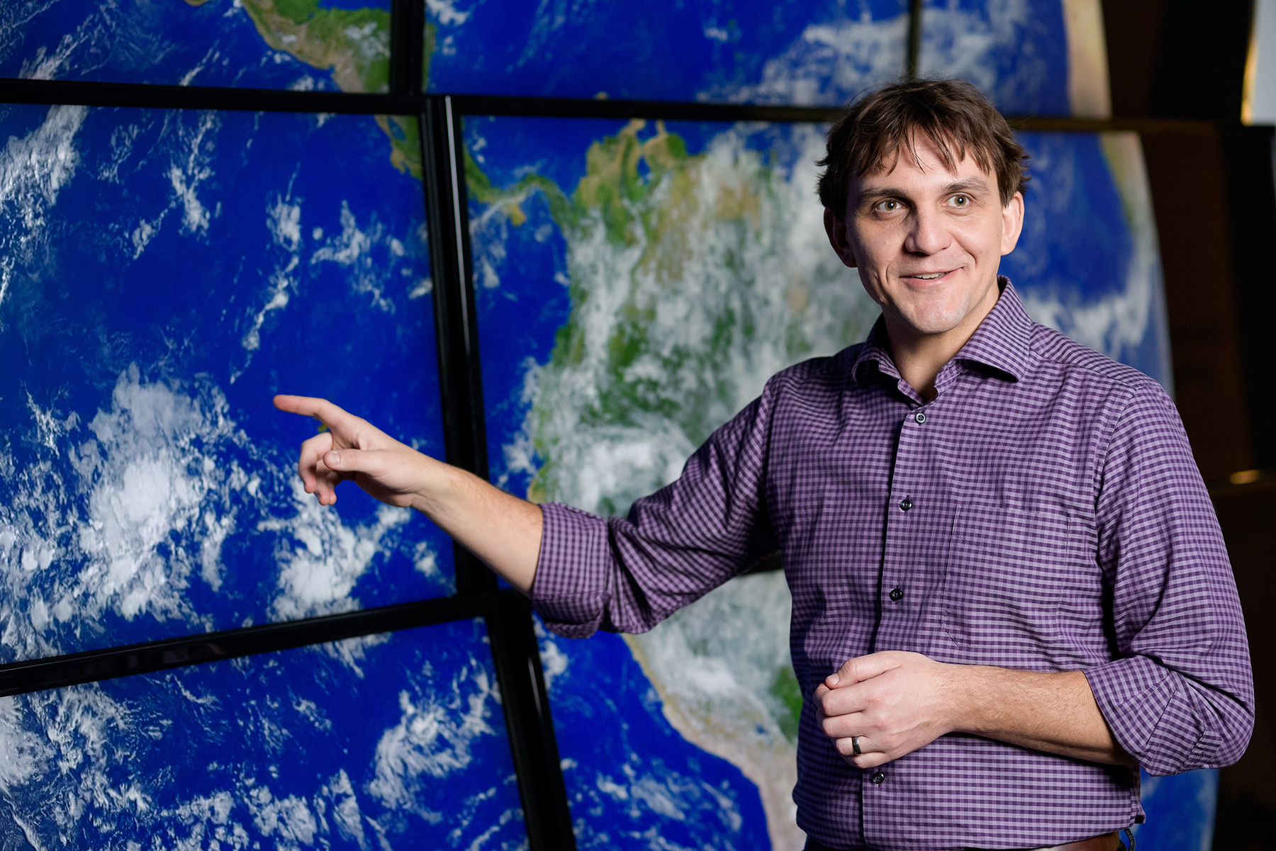 Daniel Horton in front of a world map.