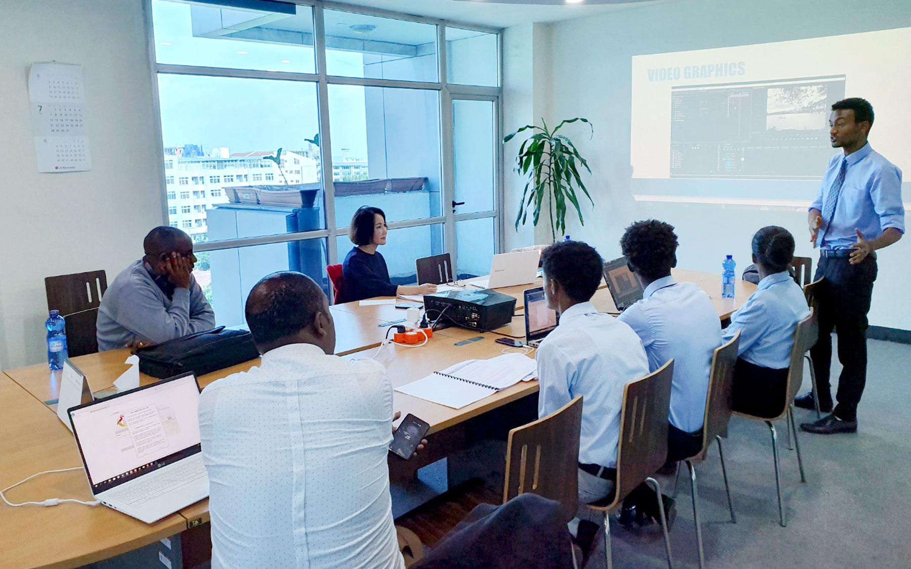 SeoHyun Bae (third from left) listens as one of the SharePlus staff members presents to his colleagues in a conference room.