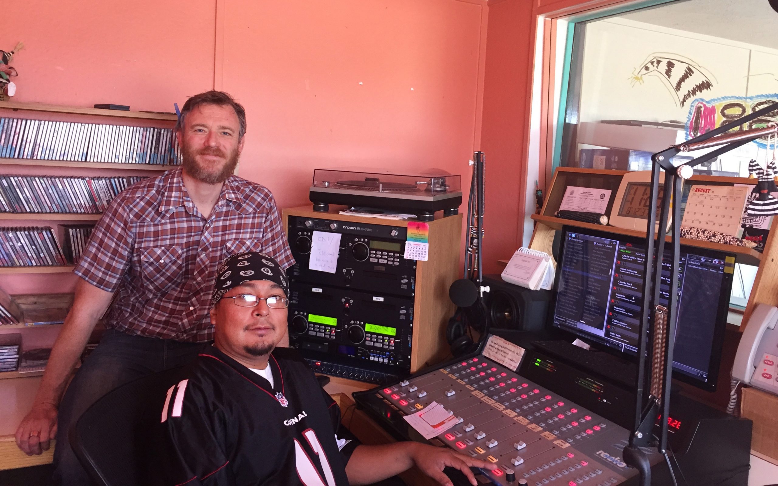 Two people inside a radio station booth.