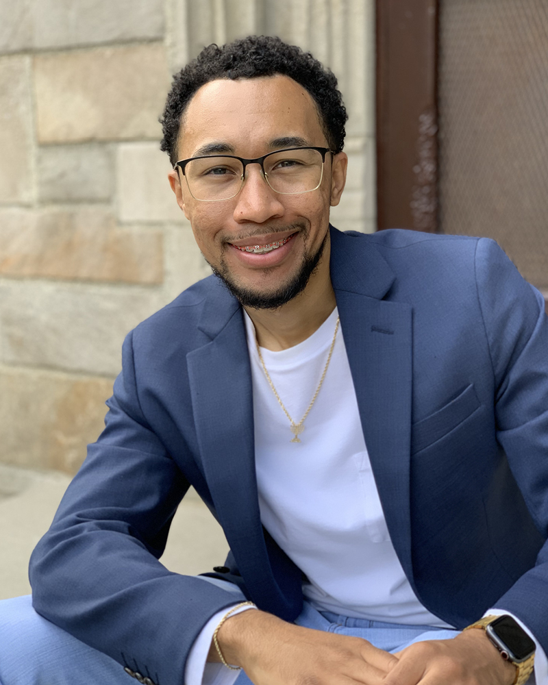 Matthew Culberson sits near a stone wall on the U-M campus.