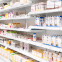 Blurred image of pharmacy shelves stocked with various bottles and boxes of health products and medications.