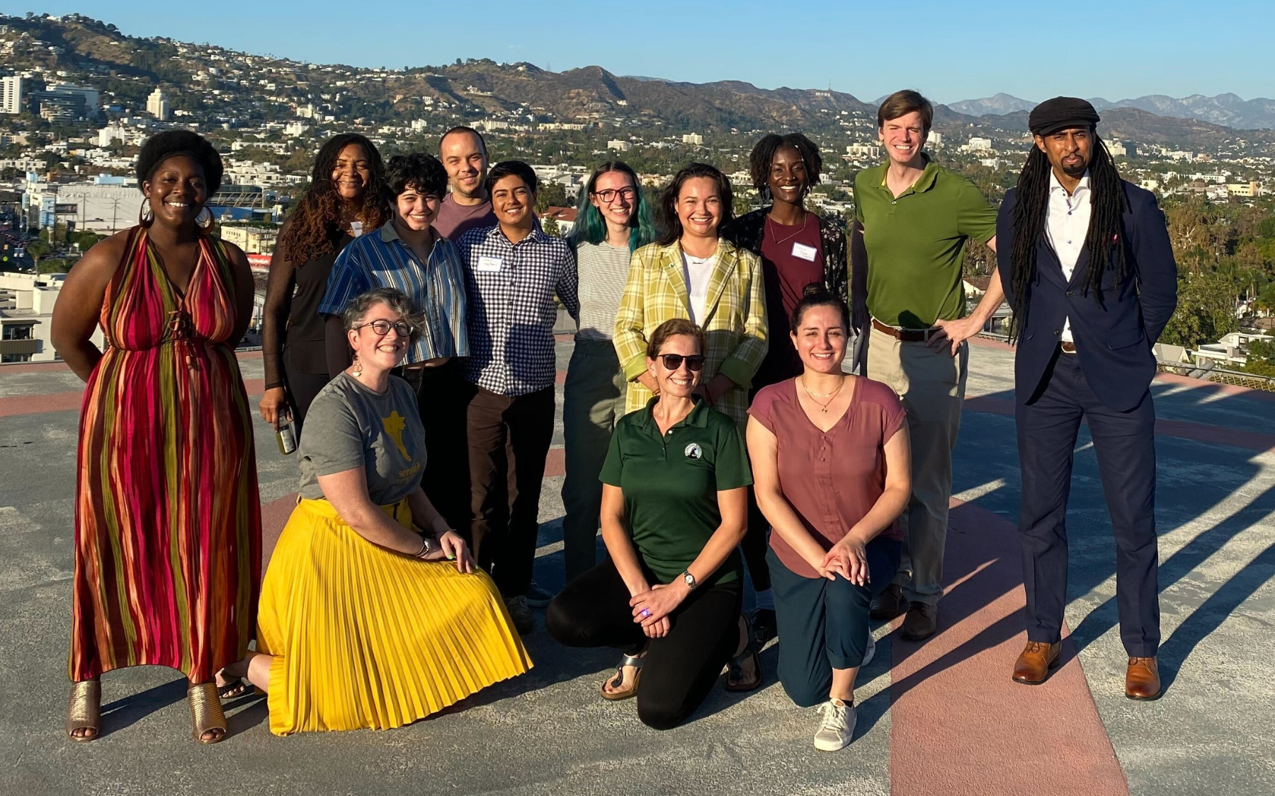 A group photo taken outdoors. Mountains are in the background.