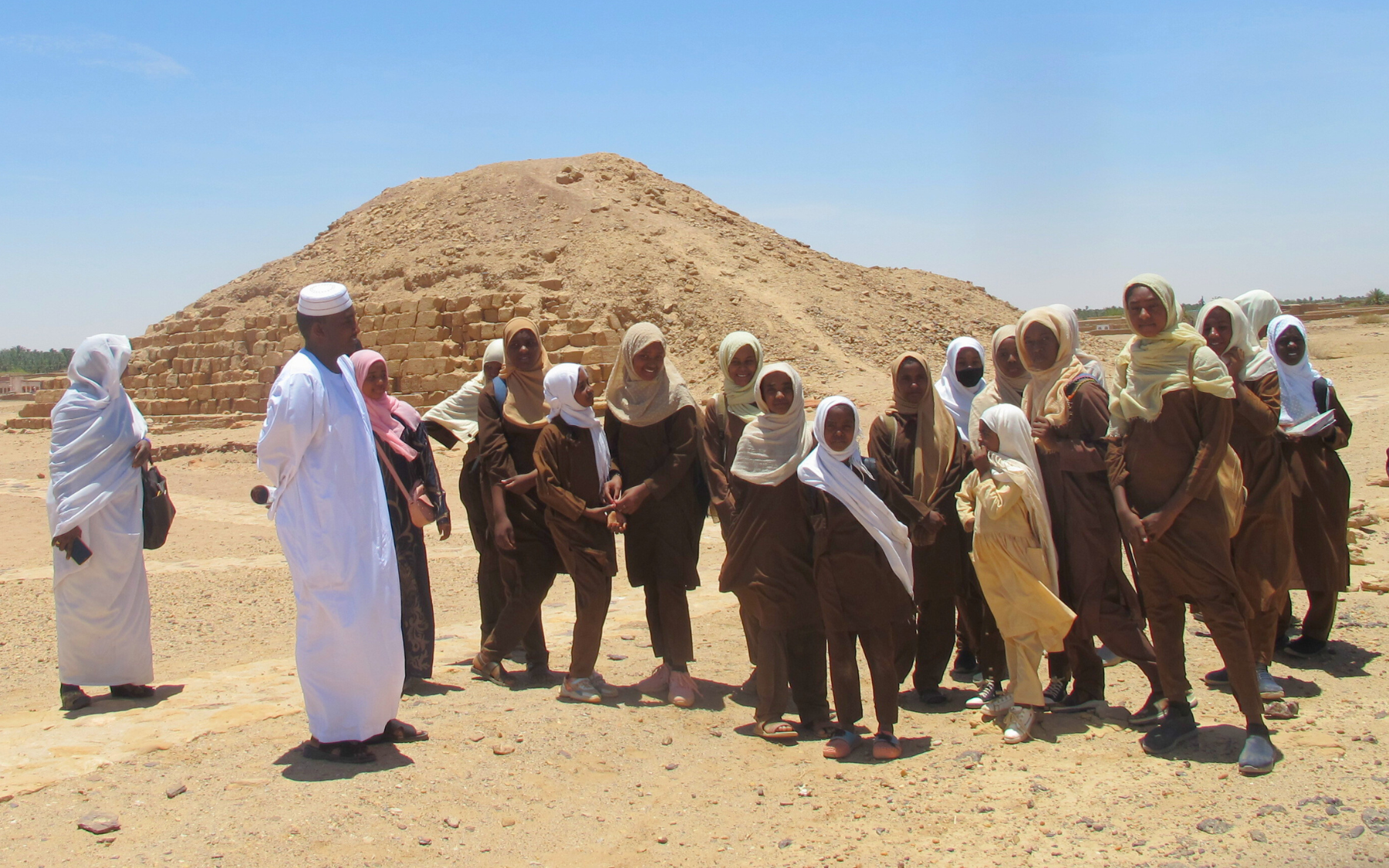 A group of people standing in front of a pyramid.