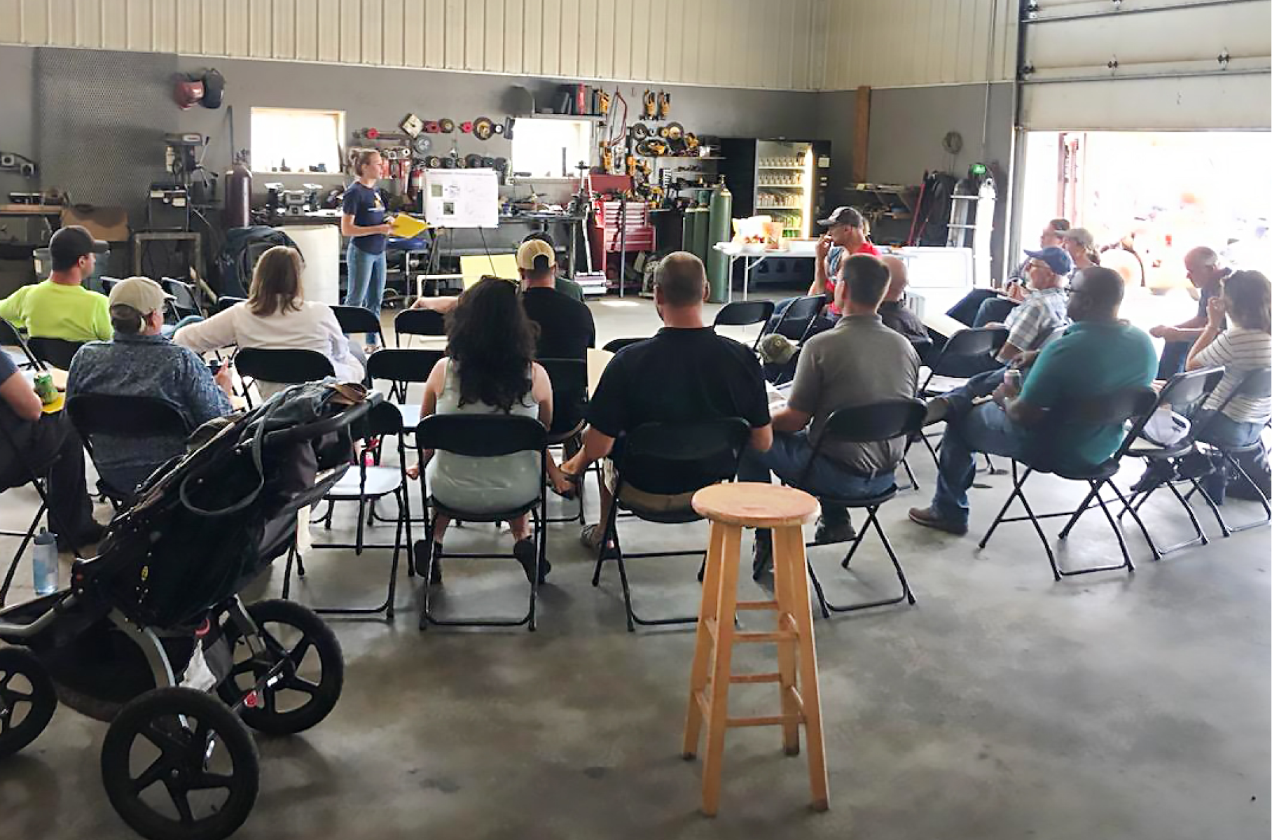 A group of people sitting in chairs in a garage.