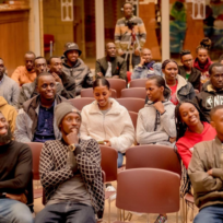 Audience seated in rows, attentively watching a presentation or event indoors.