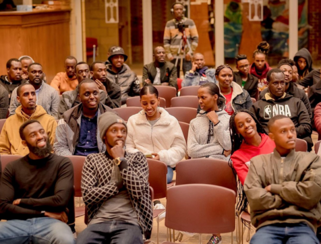 Audience seated in rows, attentively watching a presentation or event indoors.