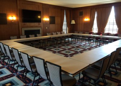 A rectangular conference table set up in a formal meeting room within the Rackham Building, featuring patterned carpet and traditional decor.