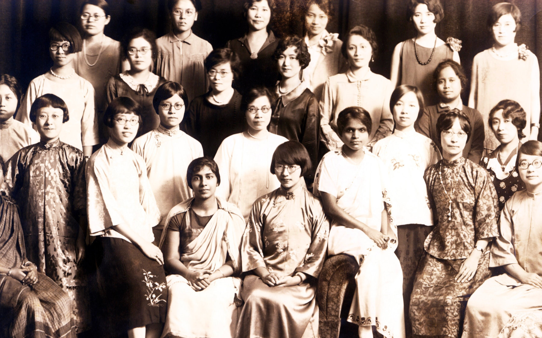 A group of women in traditional and contemporary clothing pose for a formal portrait.