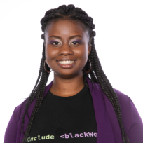 Smiling person with braided hair, wearing hoop earrings, a black T-shirt with coding text, and a purple sweater against a white background.