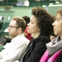 Three people sitting in a row, attentively listening in a lecture hall.