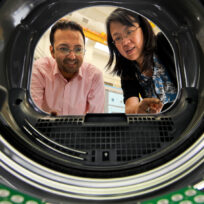 Two people looking inside a washing machine from the drum's perspective.