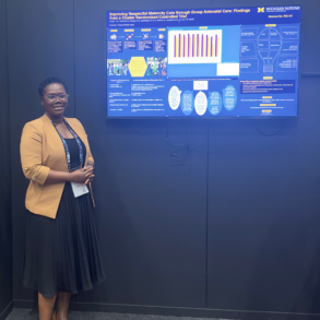A woman stands beside a research poster titled “Improving Respectful Maternity Care through Group Antenatal Care” at a conference. The poster displays charts and information.