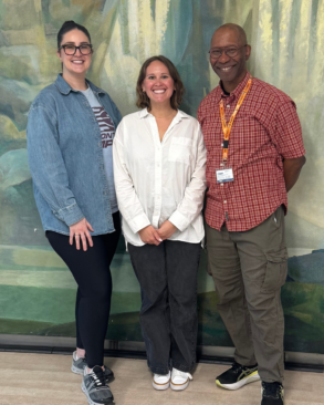 Three colleagues smile for a photo.