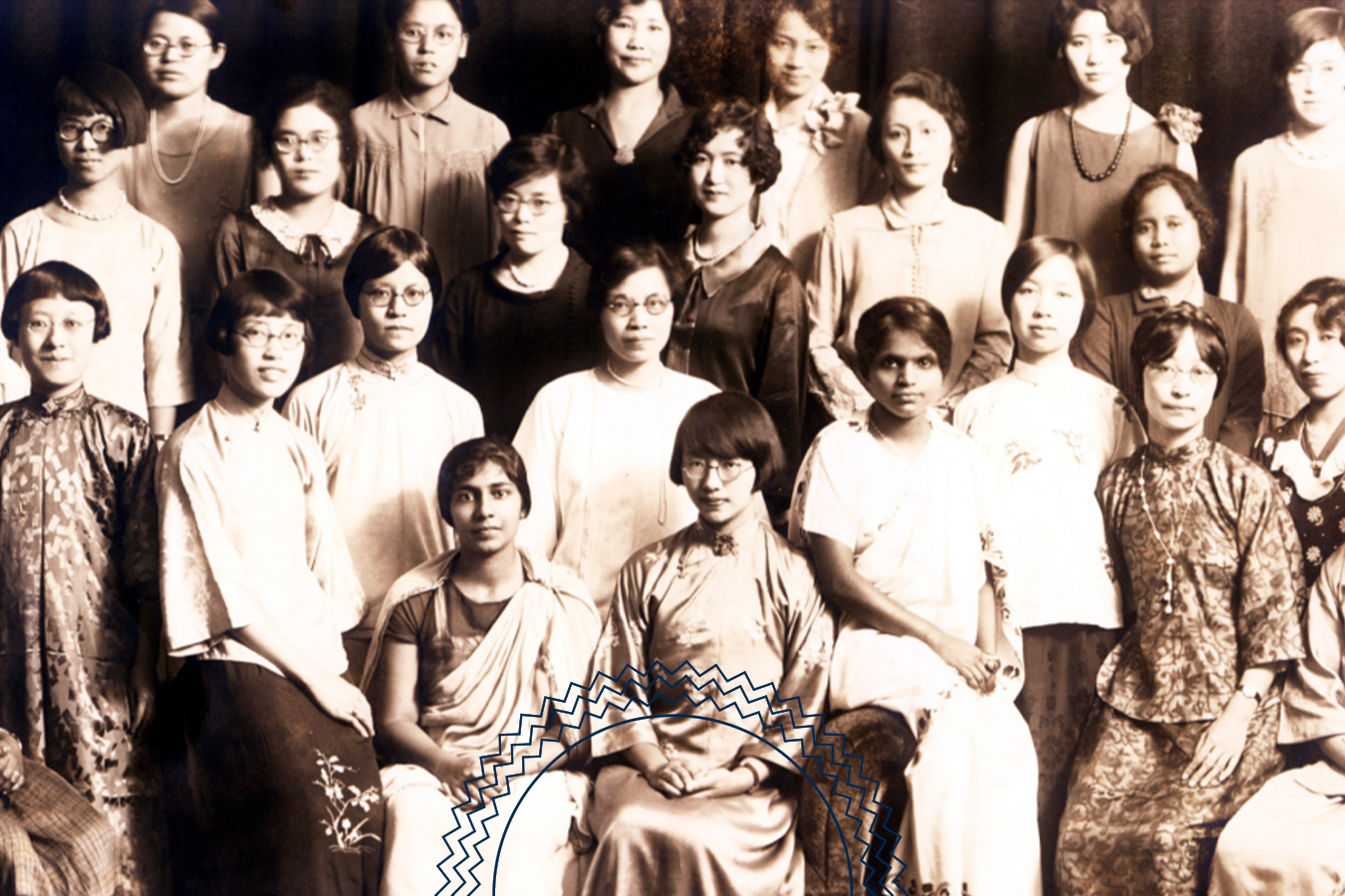 A vintage group photo of women in formal attire, arranged in three rows, facing the camera against a dark backdrop.