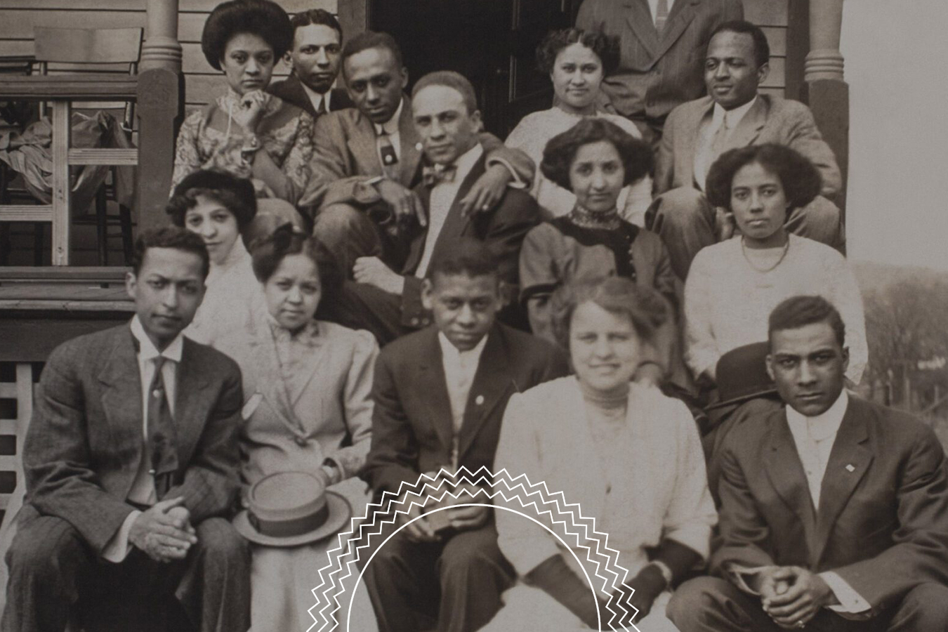A vintage black and white photo showing fifteen people seated and standing on steps, dressed in early 20th-century formal clothing, posing for a group portrait.