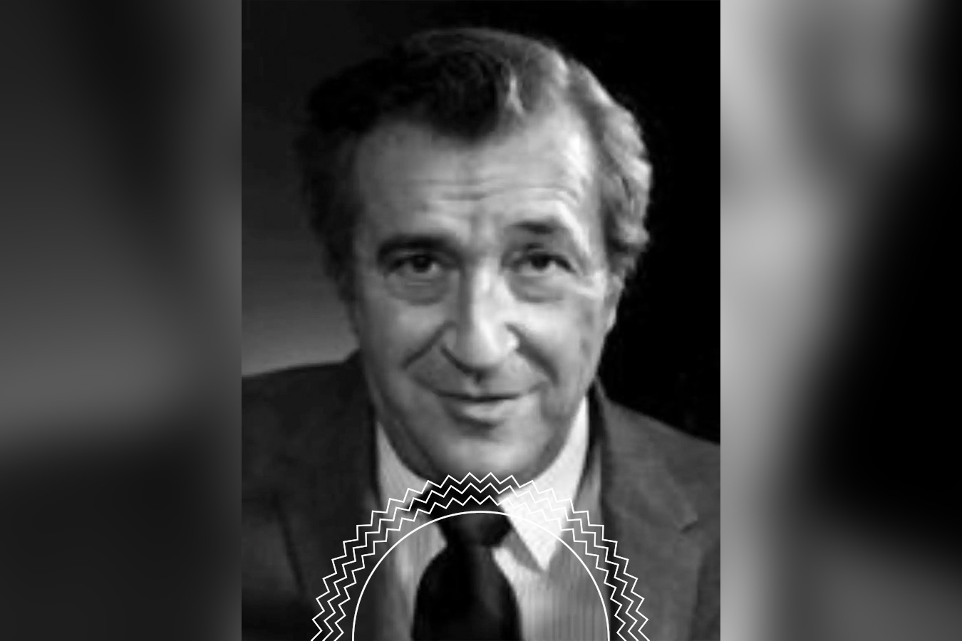 A grayscale portrait of an older man in a suit and tie, with short hair, looking at the camera with a neutral expression.