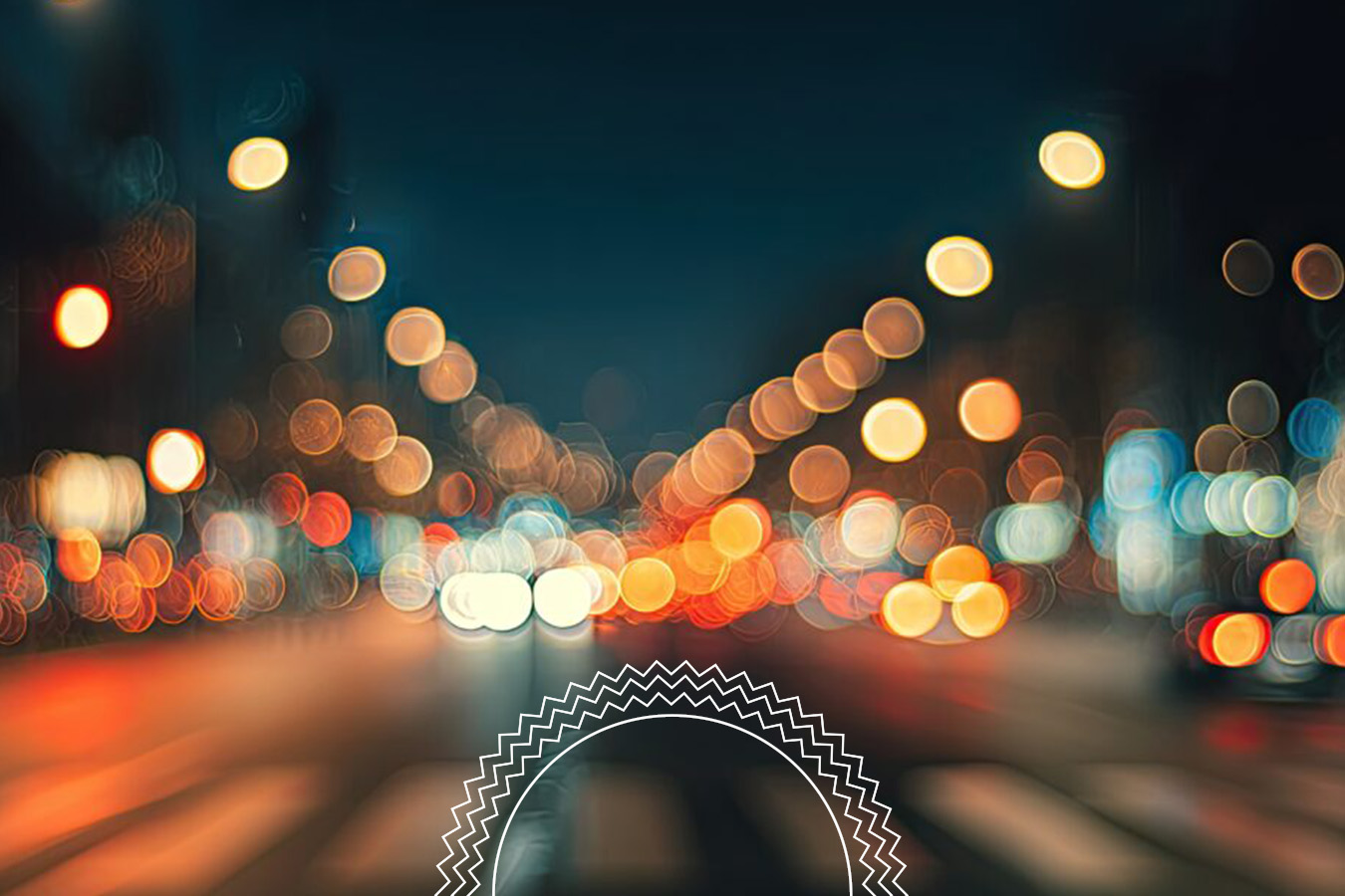 A city street at night with blurred, out-of-focus lights creating a bokeh effect. Traffic and streetlights are visible, but no distinct details.