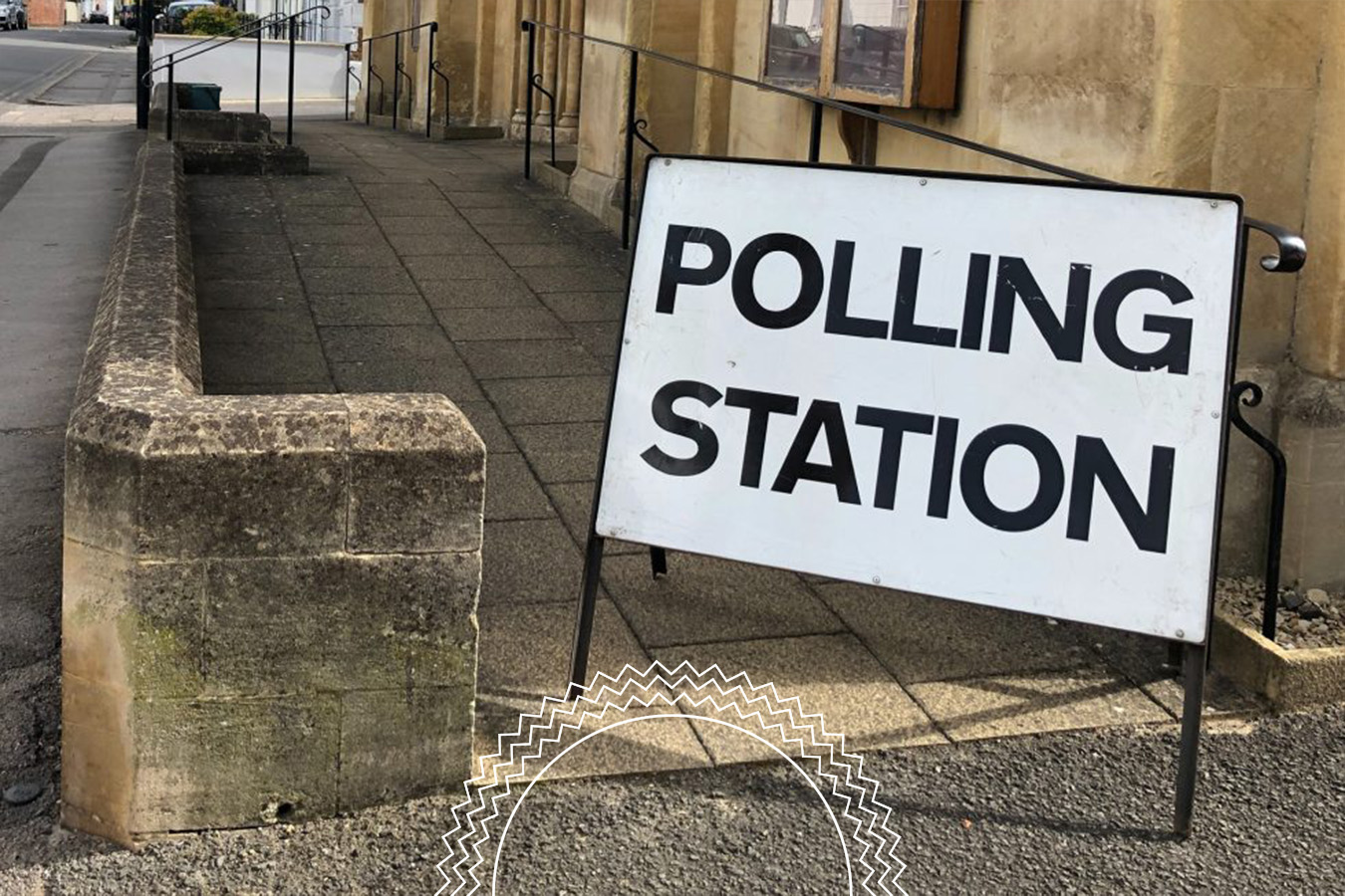 A large sign reading “Polling Station” stands on a sidewalk next to a stone building entrance.
