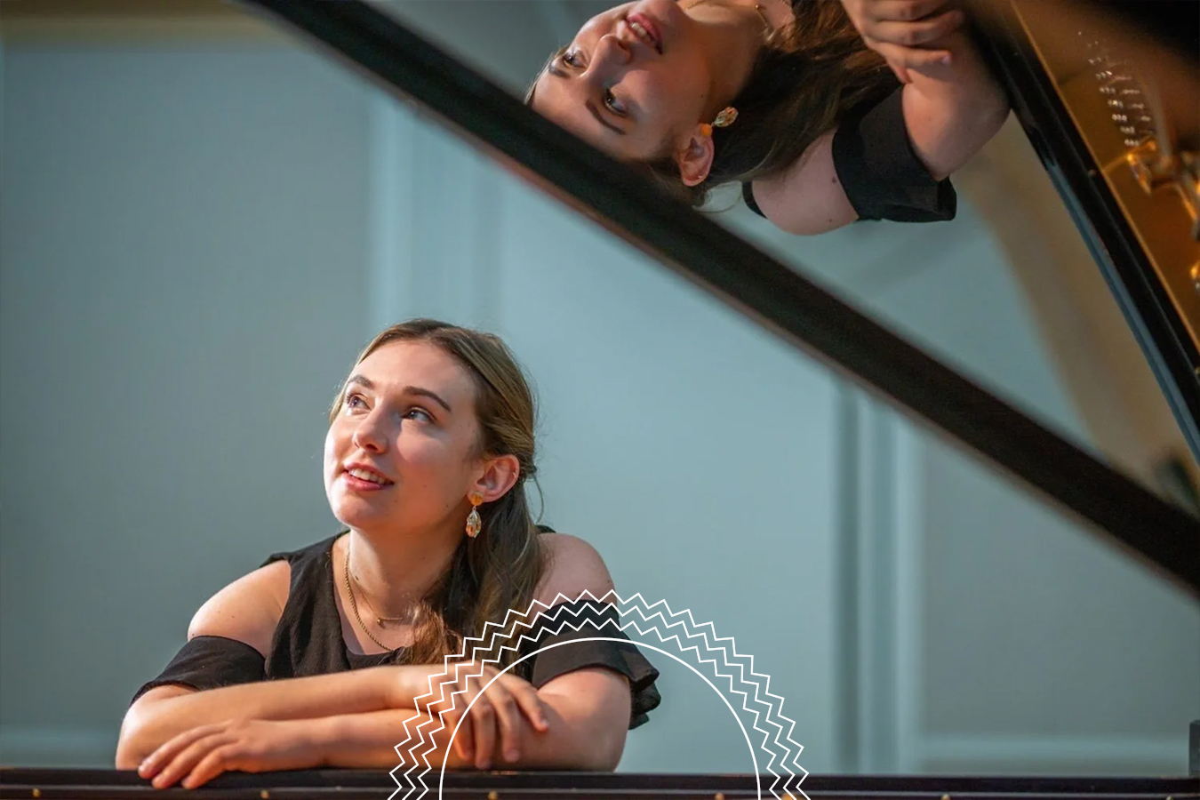 A woman leans on a piano, looking upward, with her reflection visible on the inside of the piano lid.