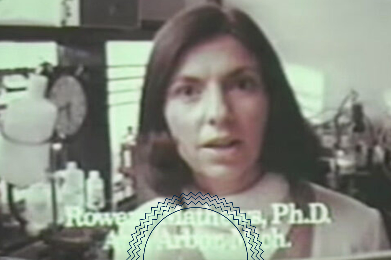 A woman stands in a laboratory setting, with scientific equipment visible in the background. Text on the image partially reads, “Rowe Matthews, Ph.D., Ann Arbor, Mich.”.