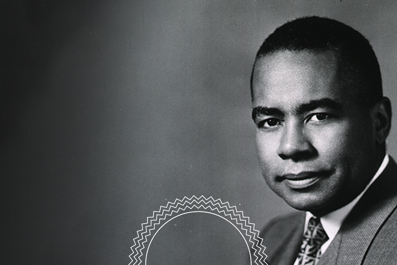 Black and white portrait of a man in a suit and tie, looking at the camera with a neutral expression, against a plain background.