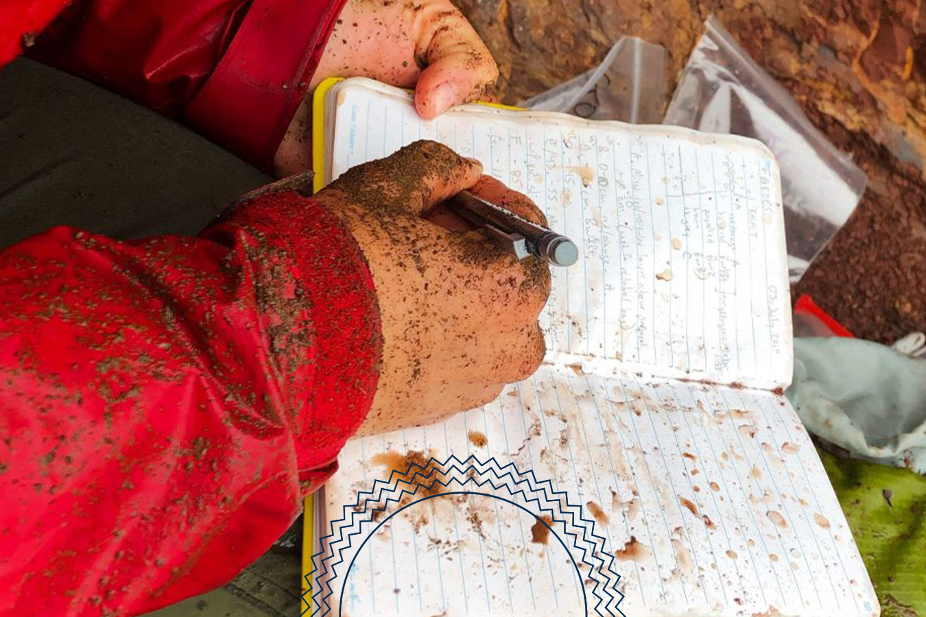 A person with muddy hands writes in a wet, dirt-stained notebook while wearing a red jacket.
