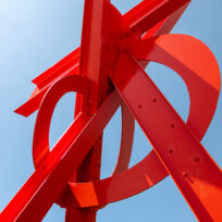 A red metal sculpture against a blue sky