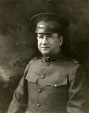 Black and white portrait of a man in a United States military uniform and round glasses.